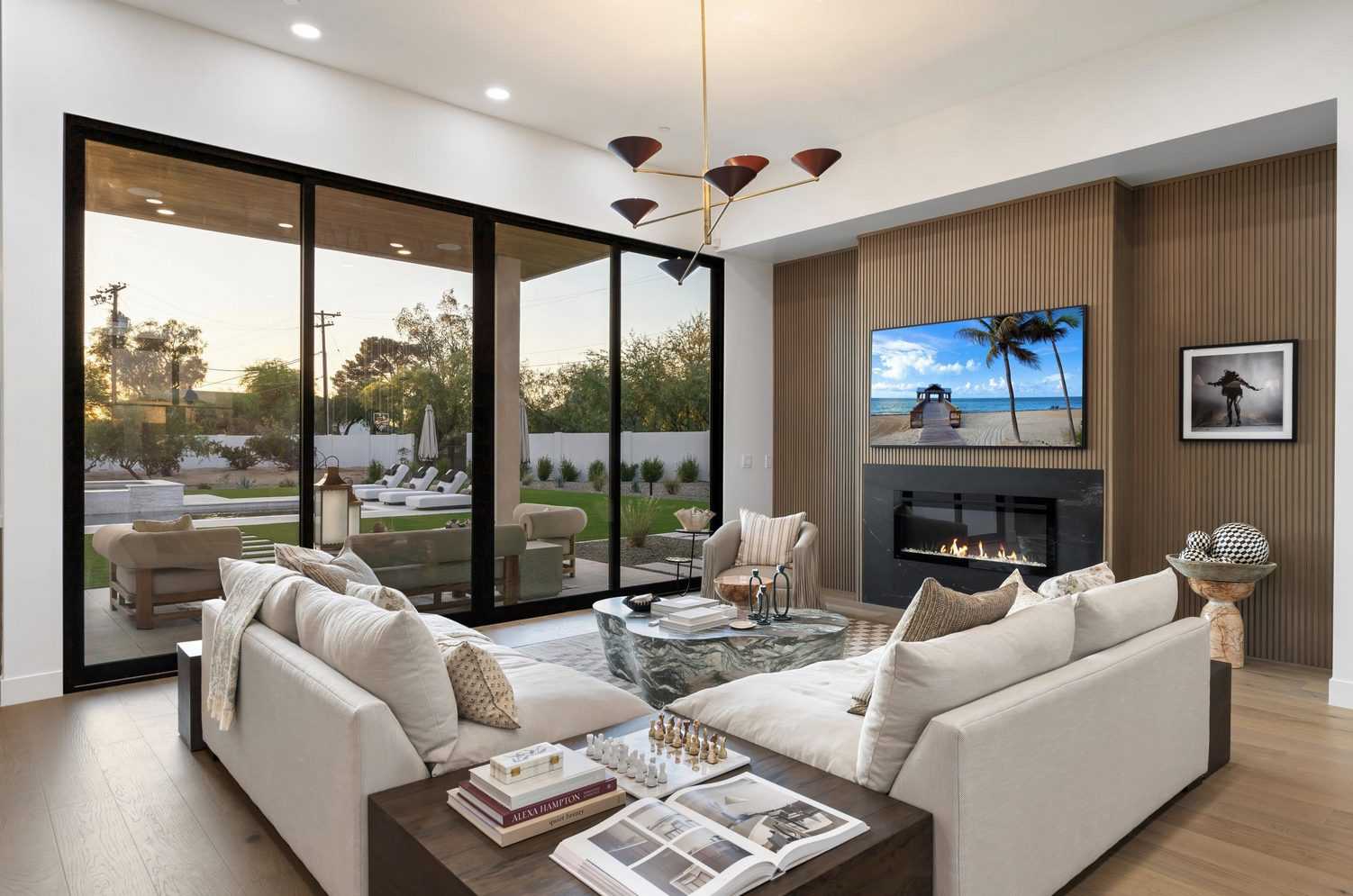 Living room with sliding glass walls open to a covered patio and pool